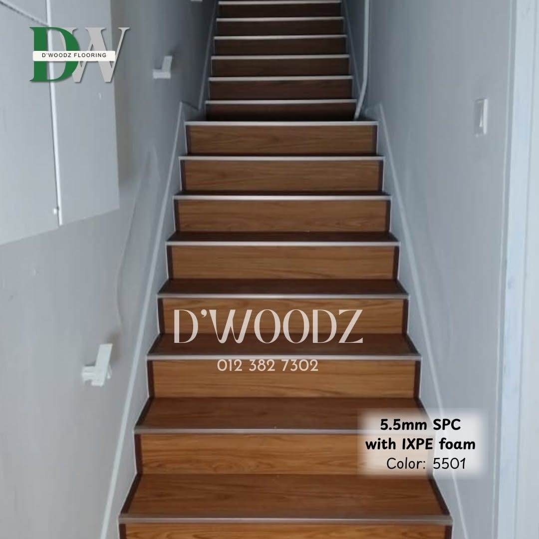 A mid-brown clad staircase rising against a white wall, each tread edged with a thin metal profile; the D'Woodz watermark and product label in frame.