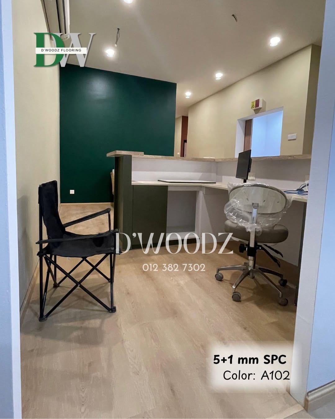 An office pantry with a dark green wall, a counter and a chair on a pale oak-toned plank floor; the D'Woodz watermark and product label in frame.